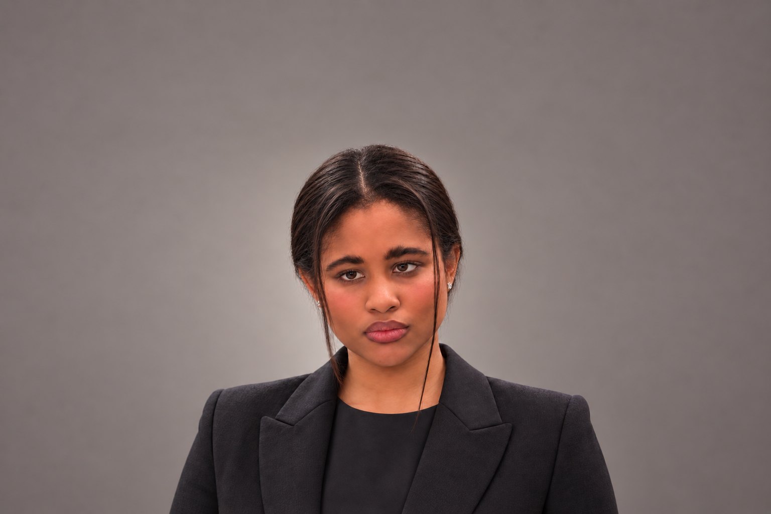 Portrait of Heidy Smith in a black tailored jacket against a grey studio backdrop.